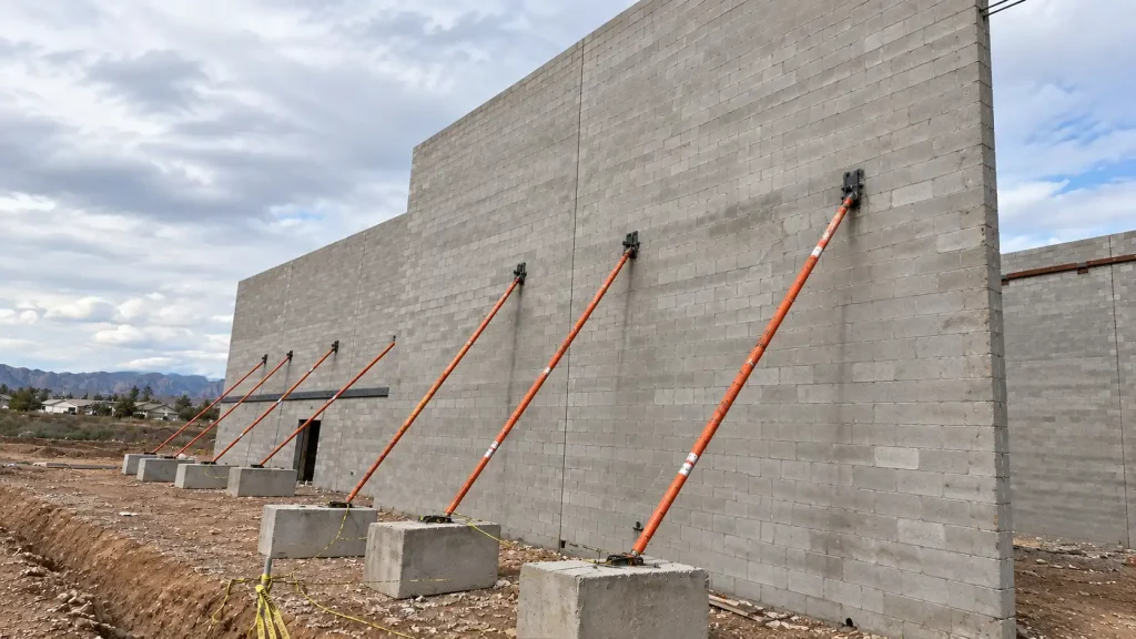 Inclined raking shores supporting an existing wall